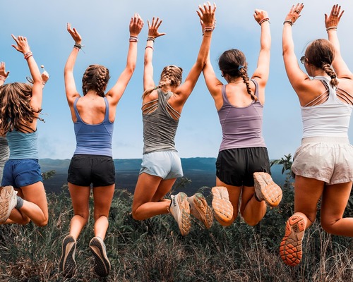 students jumping in excitement on the rim of a Galapagos volcano during a student tour.